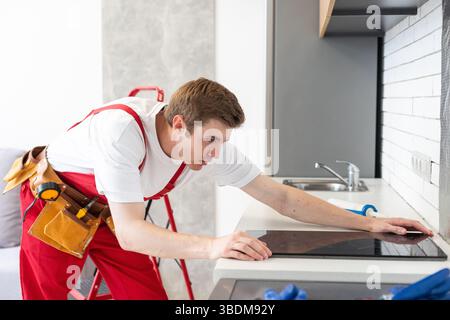 craftsman installs hob in kitchen. Household Appliance Installation Services Concept Stock Photo