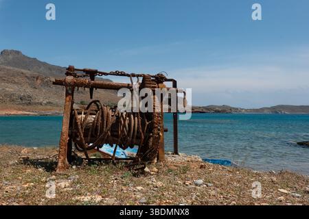 Rusted old boat winch formerly used to haul fishing boats ashore on the coast of a bay on Crete, Greece Stock Photo