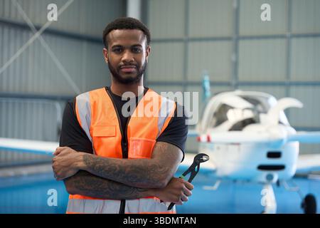 Aircraft mechanic holding pliers posing in hangar with light aircraft Stock Photo