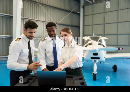 Aircraft maintenance crew using laptop in hangar with small airplane Stock Photo