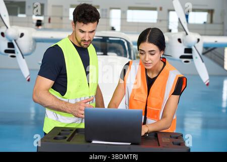 Aircraft mechanics using laptop for maintenance in hangar Stock Photo