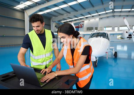 Aircraft mechanics using laptop in hangar with small airplane Stock Photo