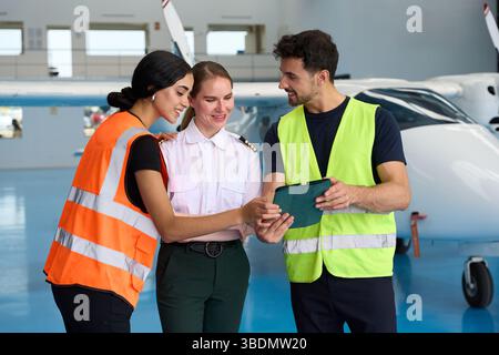 Aviation students and pilot using tablet in hangar Stock Photo
