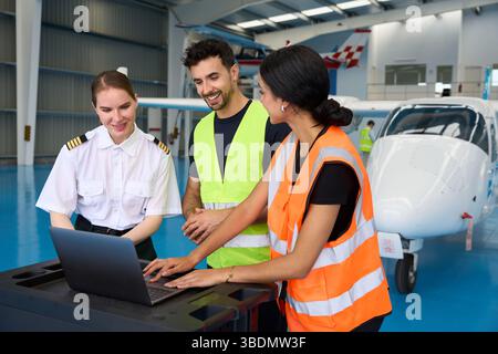 Aviation students and pilot using laptop in aircraft hangar Stock Photo
