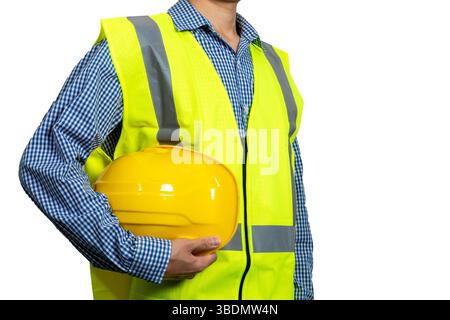 Safety workwear concept. Male hand holding yellow safety helmet. Construction worker man with reflective yellow vest isolated on white background. Stock Photo