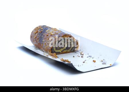 Close-up of a poppy seed roll with sugar icing and crushed nuts, partially eaten, placed on white paper tray. Ideal for bakery ads, food packaging Stock Photo
