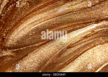 Close up view of golden shimmering cosmetic texture of gel or body spray. Background texture for backdrops or mapping. Stock Photo