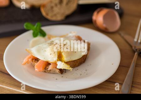 A slice of bread with lightly salted red fish and a cooked egg for breakfast. Stock Photo