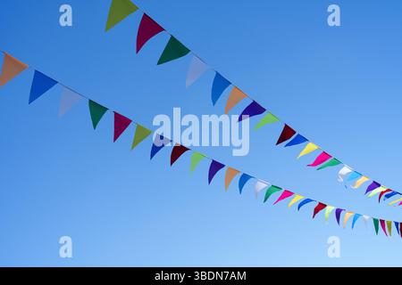Photo of colorful buntings flying against a blue sky. Festive flags. Space for text. Stock Photo