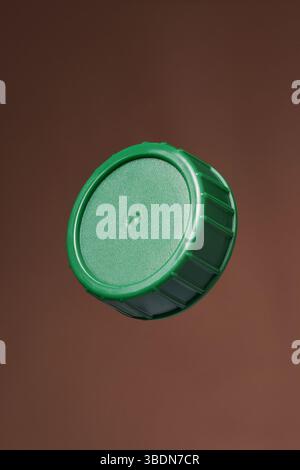 Green plastic bottle cap on a brown background. Close up. Stock Photo