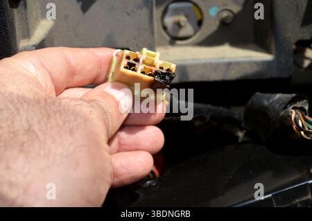 A burnt plug in the car electricity system connected to the wires that initiates electric current to car devices like air conditioner, electricity haz Stock Photo