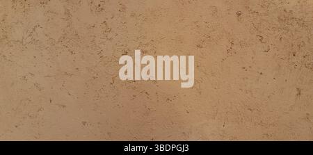 Rough concrete wall texture with a light brown color, perfect for backgrounds and providing ample copy space Stock Photo