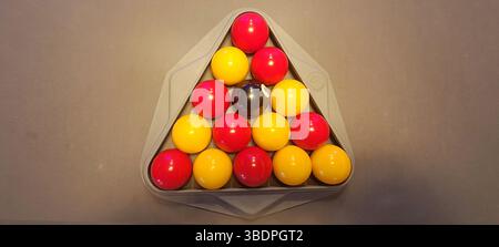 Colorful pool balls are arranged in a triangle on a billiard table, ready for the game to begin Stock Photo