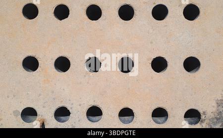 Rusty metal plate featuring evenly spaced circular cutouts Stock Photo