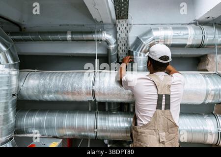 Skilled worker installing metal ductwork in a commercial building during a maintenance project Stock Photo