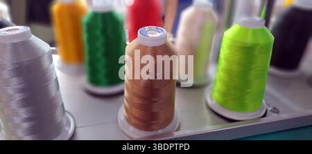 Spools of brightly colored thread are arranged on an embroidery machine, ready for use Stock Photo