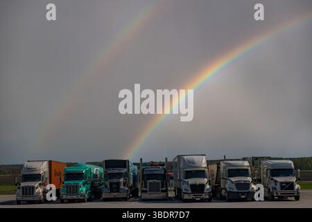 Freight lorries under a rainbow in North America Stock Photo