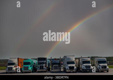 Freight lorries under a rainbow in North America Stock Photo
