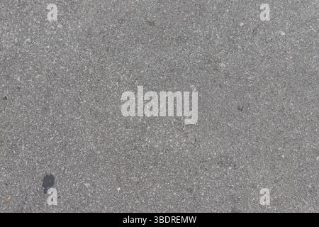 Close-up shot of a gray concrete surface with small rocks and textures. One dark spot is visible. Stock Photo