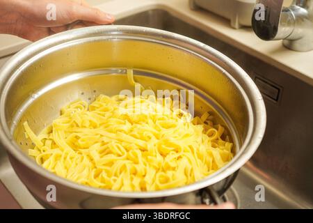 Cook tagliatelle pasta, drained in a colander Stock Photo