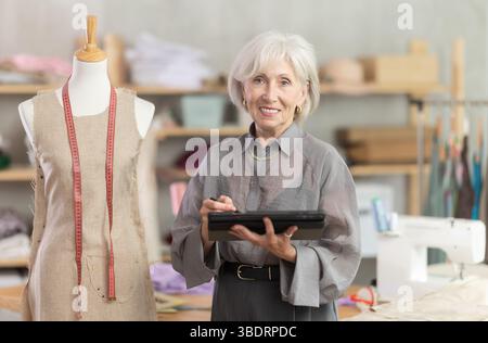 Woman dressmaker makes pattern using tablet Stock Photo