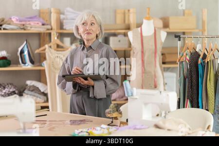 Woman dressmaker makes pattern using tablet Stock Photo