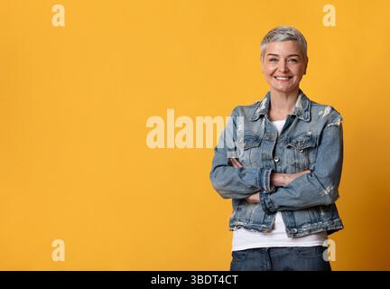 Portrait of beautiful mature woman smiling at camera over yellow background Stock Photo