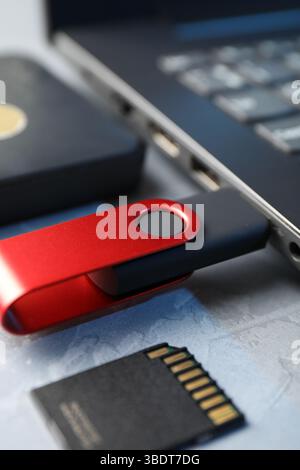 Flash drive connected to laptop, SD memory card and external hard disk on gray textured table, closeup Stock Photo