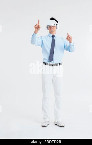 A suited man wearing a VR headset waves both hands vigorously Stock Photo