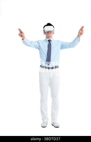 A suited man wearing a VR headset waves both hands vigorously Stock Photo