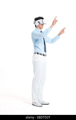 A suited man wearing a VR headset waves both hands vigorously Stock Photo