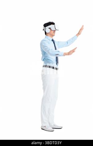 A suited man wearing a VR headset waves both hands vigorously Stock Photo