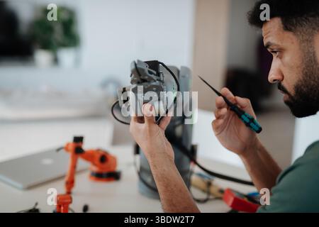 Side view of engineer building and programming a robotic arm at home. Stock Photo