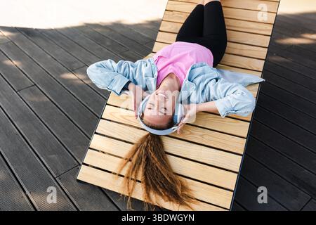 Relaxed woman listening to music lying on lounger Stock Photo
