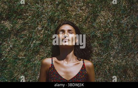 Serene woman relaxing and lying on a grass Stock Photo