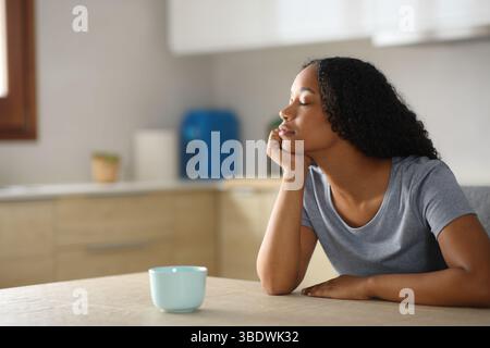 Black woman is relaxing sitting in a kitchen at home Stock Photo