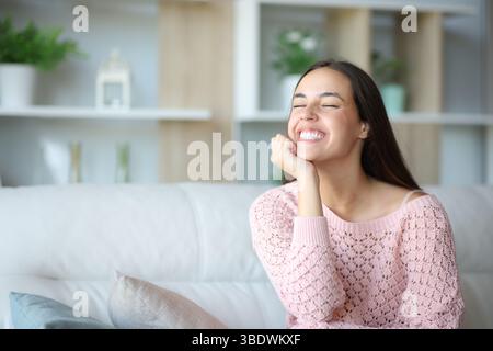 Happy woman sitting on a couch at home relaxing Stock Photo