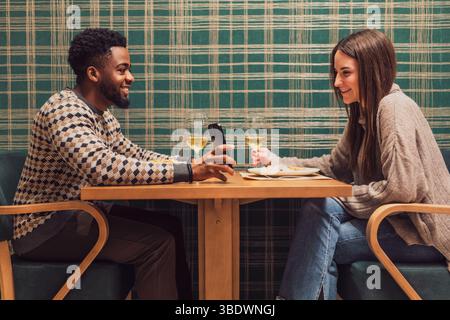 Two friends are having dinner at restaurant. They are sitting, talking and enjoying time together. Stock Photo