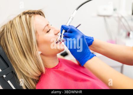 Dentist drilling the teeth of the patient. Young woman having her teeth repaired. Close up. Stock Photo