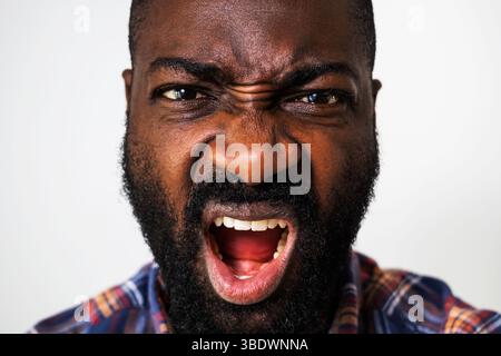 Close up portrait of angry black man who is looking at camera and shouting. Stock Photo