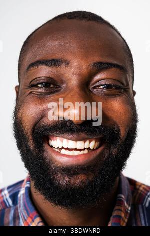 Close up portrait of happy and cheerful black man. Adult man is looking at camera and laughing. Stock Photo