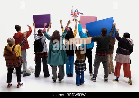 Diverse people with protest signs and UK flag stand united, raising fists from behind against white studio background Stock Photo