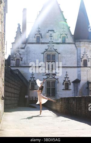 Ballet dancer leaping in sunlight by historic French castle Stock Photo