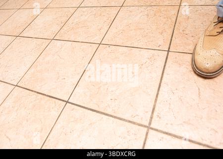 Businessman wearing beige perforated shoes standing on a ceramic tile floor in an office building, large copyspace Stock Photo