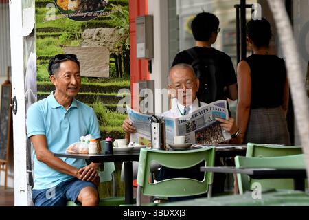 Old Singaporean man reading newspaper on chair at Chinese temple,Singapore,Asia. Stock Photo