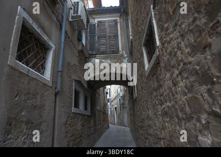 Narrow grey passage in Old Town, unplastered walls. Koper, Slovenia. Stock Photo