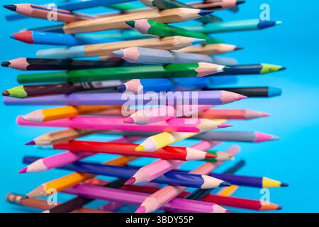 Stacked colored crayons stacked in the shape of a tower close up detail on blue Stock Photo