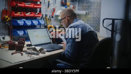Handyman Checking Real-Time Stocks and Exchange Market Charts Using Laptop Computer and Phone, Watching Online Trading Tutorial on Digital Tablet. Man Studying Trading Remotely Working in Workshop. Stock Photo