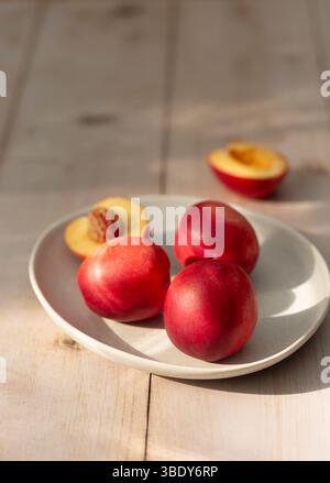 Fresh, ripe nectarines on a plate on a wooden table Stock Photo