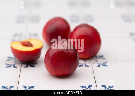 Shiny, ripe nectarines on white and blue tiles Stock Photo